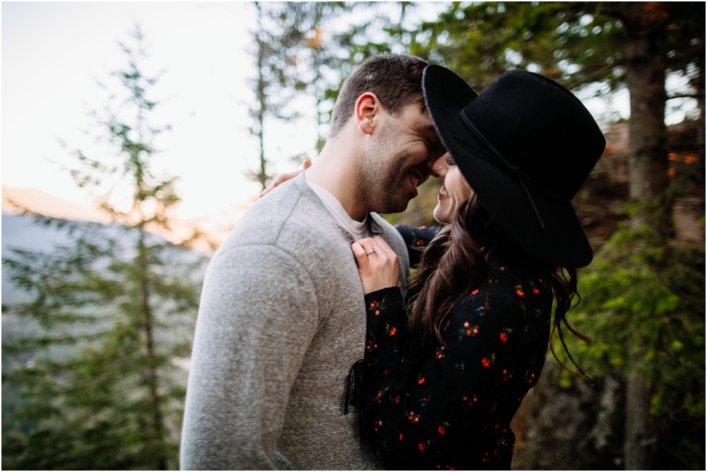 couple stands in the trees and smiles Rattlesnake Ledge Engagement