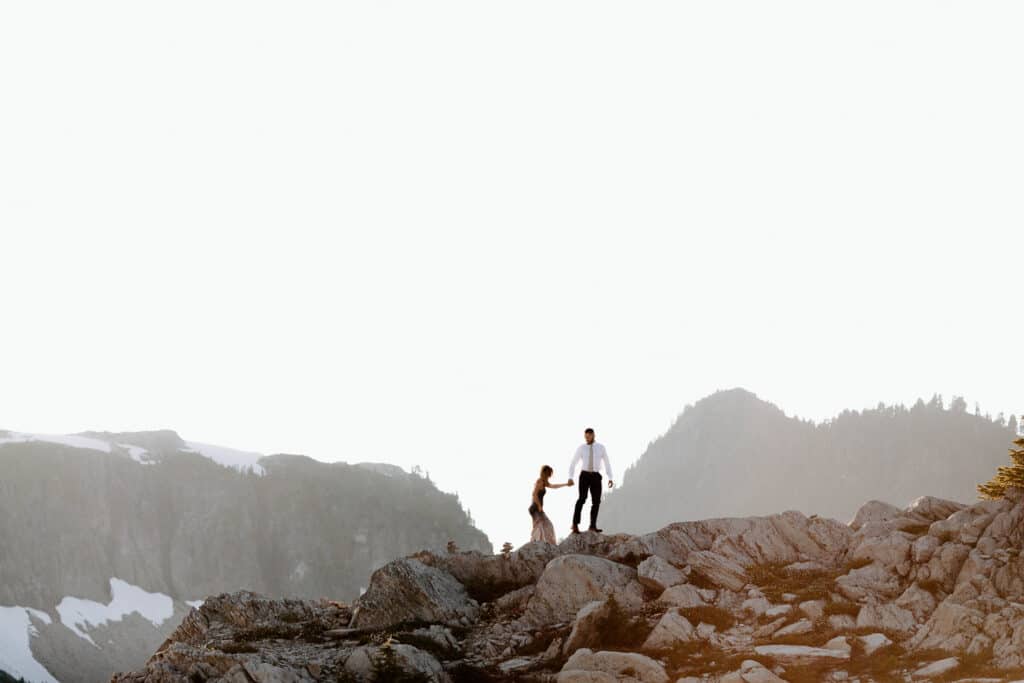 Couple climbs on rocks at Artist Point during north cascades elopement