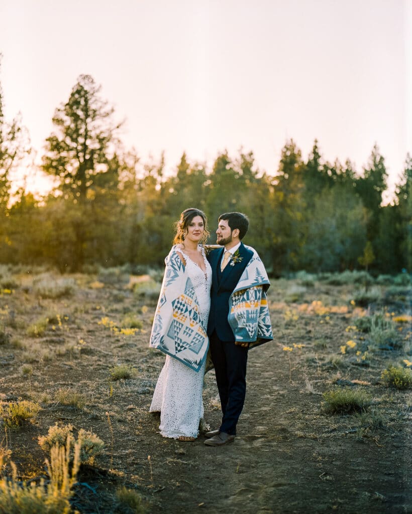 couple poses together in sunset on film with blanket in desert during backyard elopement