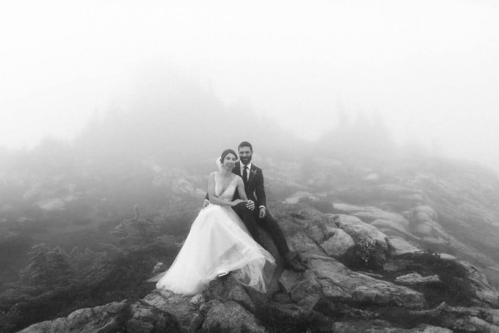 bride and groom sit on a rock during their artist point wedding
