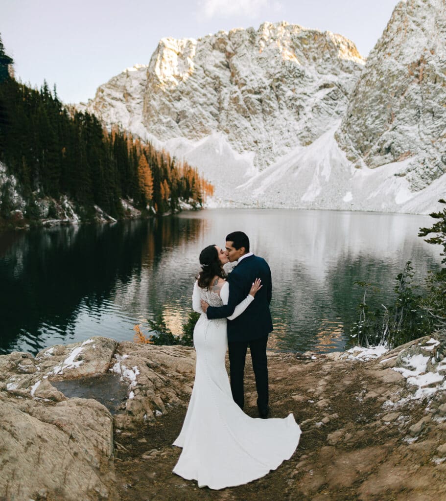 couple kisses next to mountain lake during north cascades elopement