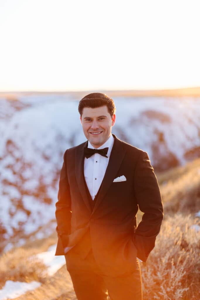 groom smiles at the camera at sunset in Montana