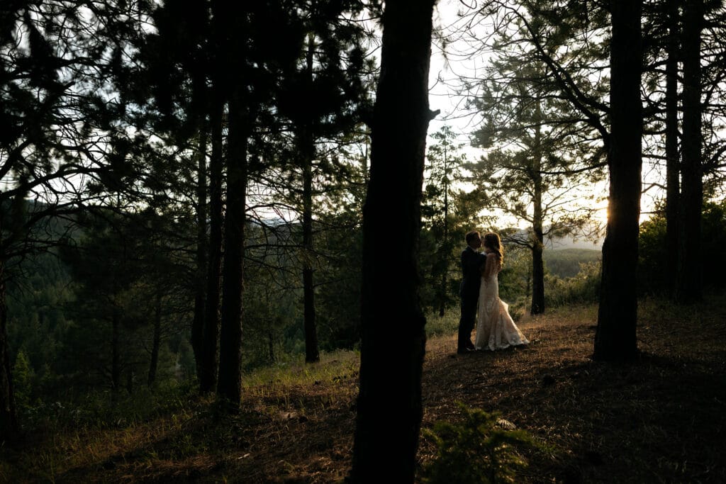 couple kisses between pine trees at Suncadia resort wedding in Cle Elem Washington.