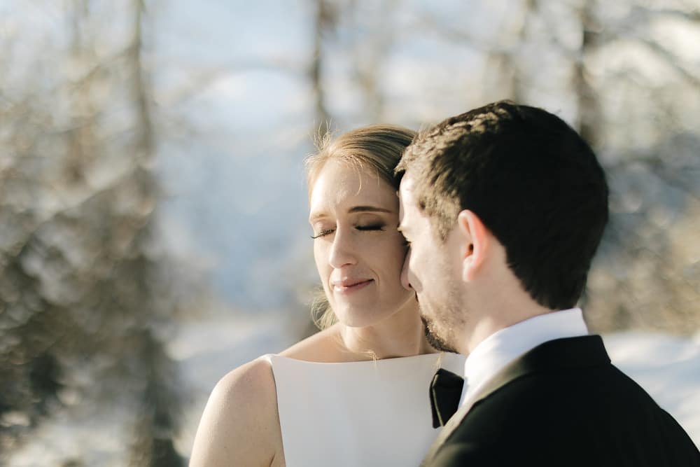 bride and groom pose in the snow during winter elopement