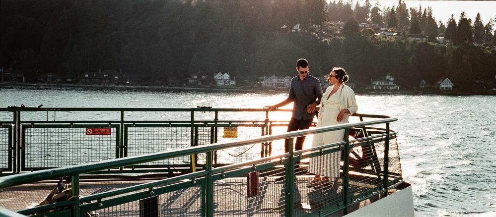 couple poses on stern of ferry during elopement at sunset on film